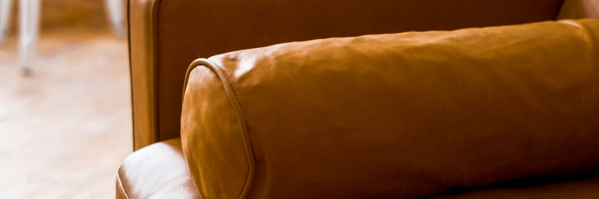 A leather sofa with a round cushion in a quiet, light room
