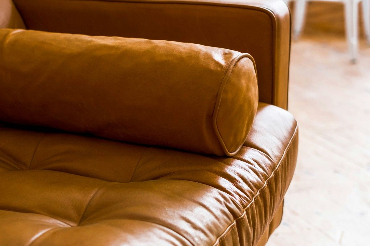 A leather sofa with a round cushion in a quiet, light room